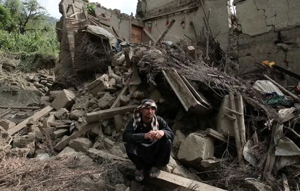 Una víctima del terremoto del domingo se sienta junto a los escombros de una casa dañada en Kunar. Foto: EFE