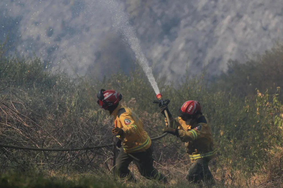 Fotografía de archivo, tomada en septiembre de 2024, de un par de bomberos al atender un incendio forestal, en inmediaciones de Quito (Ecuador). Foto: EFE