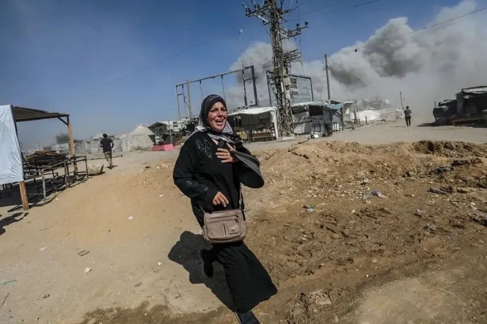Una mujer palestina corre a refugiarse tras un ataque aéreo israelí este lunes en el oeste de la Ciudad de Gaza. Foto: EFE