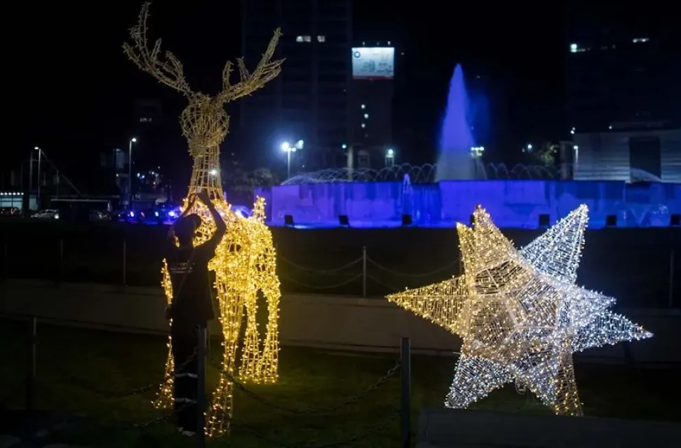 Un hombre trabaja en la instalación de una decoración navideña en Caracas (Venezuela). Foto: EFE