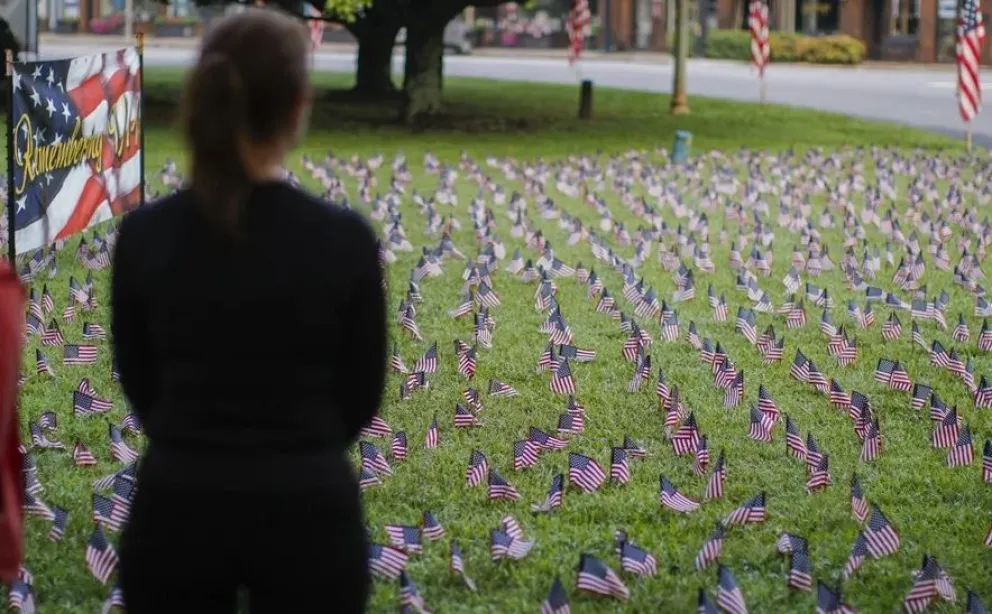 Una mujer observa banderas en el césped durante la ceremonia de homenaje a las víctimas del 11S en Avondale Estates, Georgia. Foto: EFE 