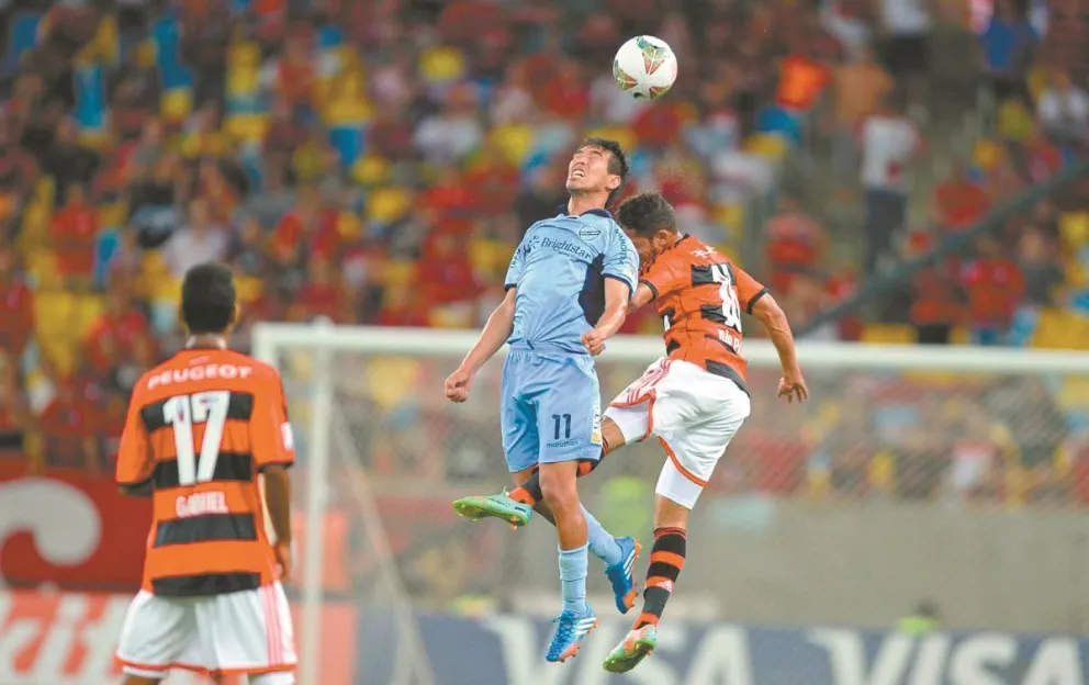 Gerardo Yecerotte (de celeste), de Bolívar, cabecea la pelota en el partido contra Flamengo en Río de Janeiro, en 2014. Foto: Internet.