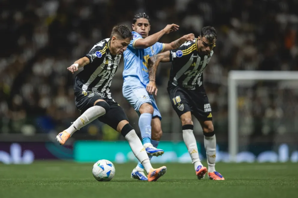 Cataño (centro), de Bolívar, entre dos jugadores del Atlético Mineiro. Foto: CAM.