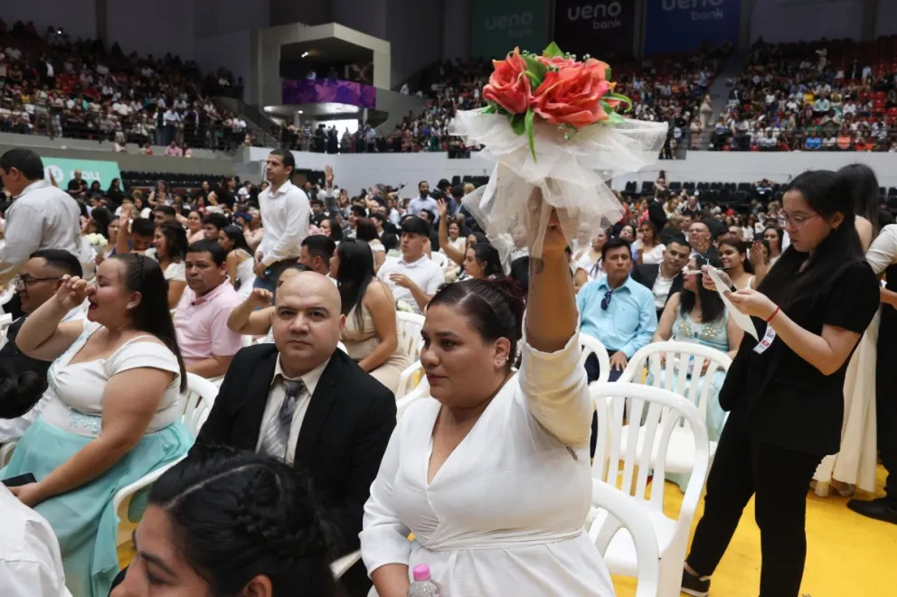 Una novia levanta su ramo matrimonial durante la más grande boda colectiva en Paraguay, este sábado, 4 de octubre, en la Secretaría Nacional de Deportes, en Asunción (Paraguay). Foto: EFE