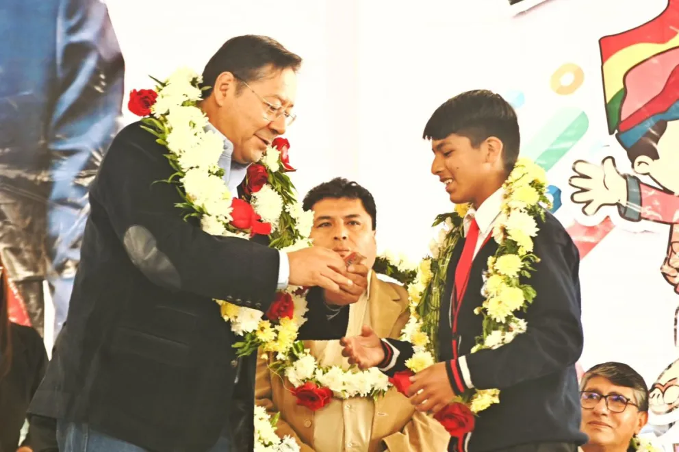 Luis Arce entrega el bono Juancito Pinto a un niño este lunes en Sucre. Foto: @luchoxbolivia