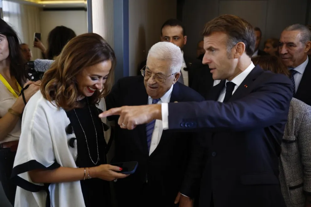 El presidente francés, Emmanuel Macron (derecha) y el de la Autoridad Nacional Palestina, Mahmud Abás (centro) hablan con la parlamentaria francesa Amelia Lakrafi tras su llegada. Foto: EFE 