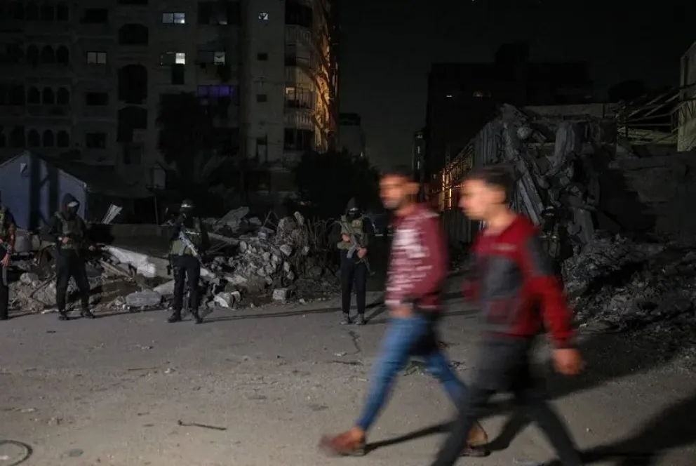 Combatientes del brazo armado de Hamas vigilan la entrega de restos de rehenes israelíes en la ciudad de Gaza. Foto: EFE