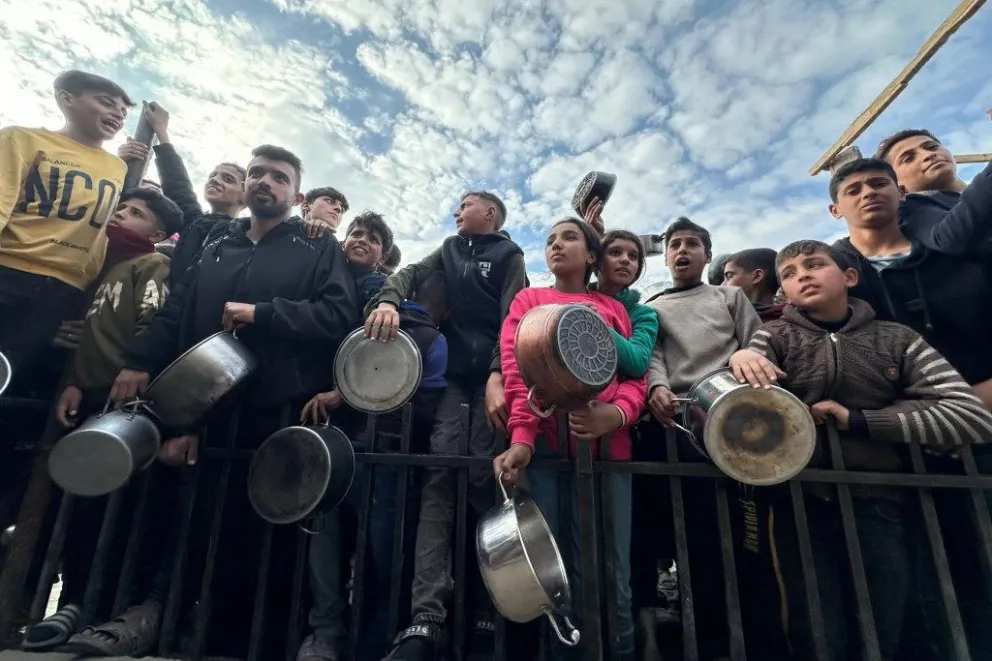 Los menores compiten para acercar sus cacerolas vacías mientras los trabajadores entregan las raciones de comida, en una imagen de archivo. EFE