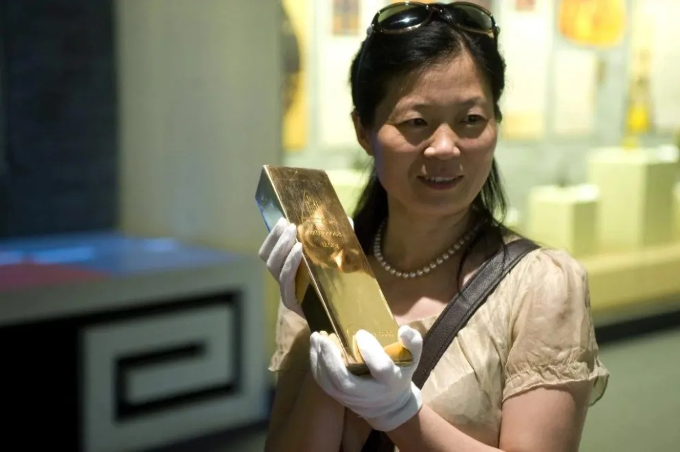 Una mujer posa para una foto con un lingote de oro de 12,5 kilos, en una imagen de archivo. EFE