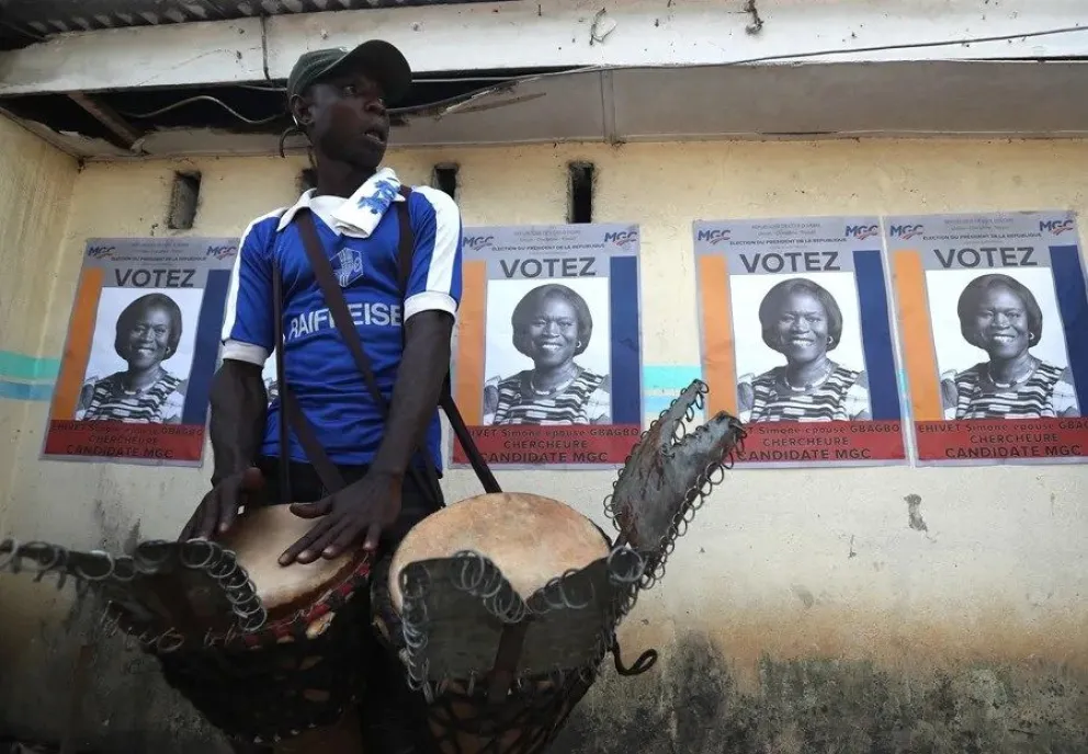 Un simpatizante toca tambores junto a carteles de la ex primera dama de Costa de Marfil, Simone Ehivet Gbagbo. EFE/EPA