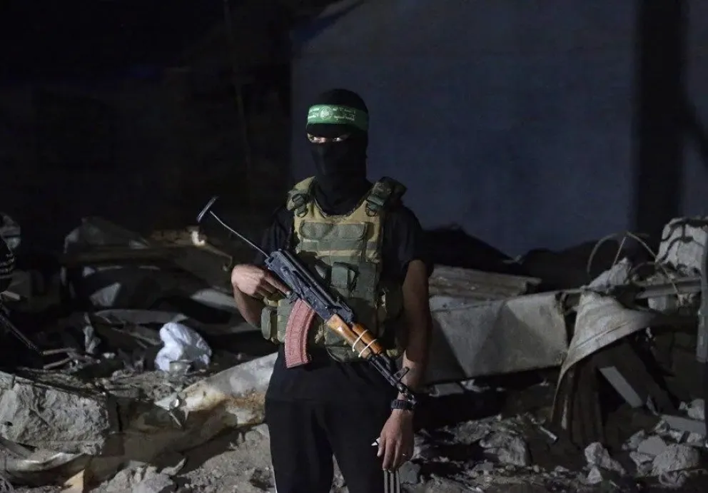 Combatientes palestinos de las Brigadas Izz ad-Din al-Qassam de Hamás vigilan mientras llegan los restos de los rehenes israelíes entregados por Hamás. EFE/EPA