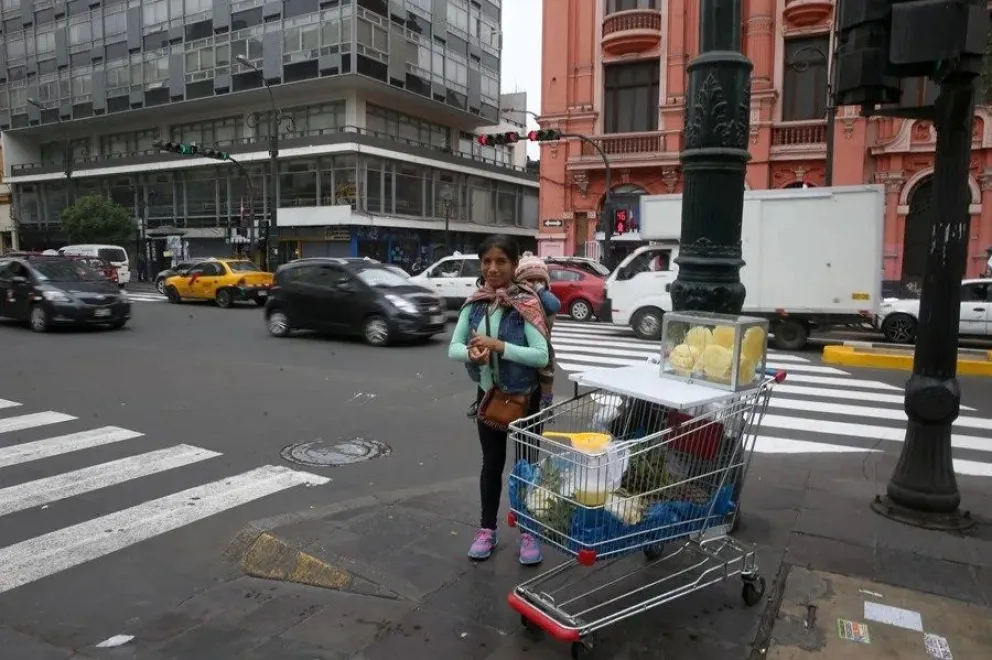 Una mujer en una esquina de la Colmena, ahora conocida como Nicolás de Piérola, en el centro histórico de la ciudad de Lima (Perú). EFE