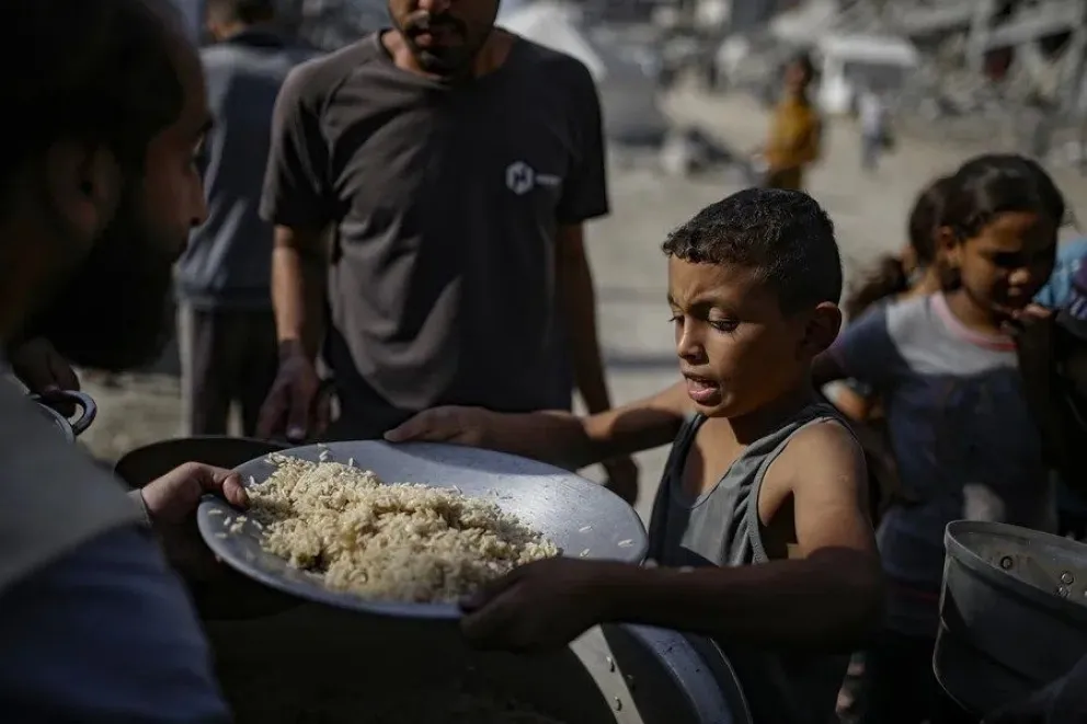 Niños palestinos reciben alimentos de un comedor social en la ciudad de Gaza. EFE/EPA