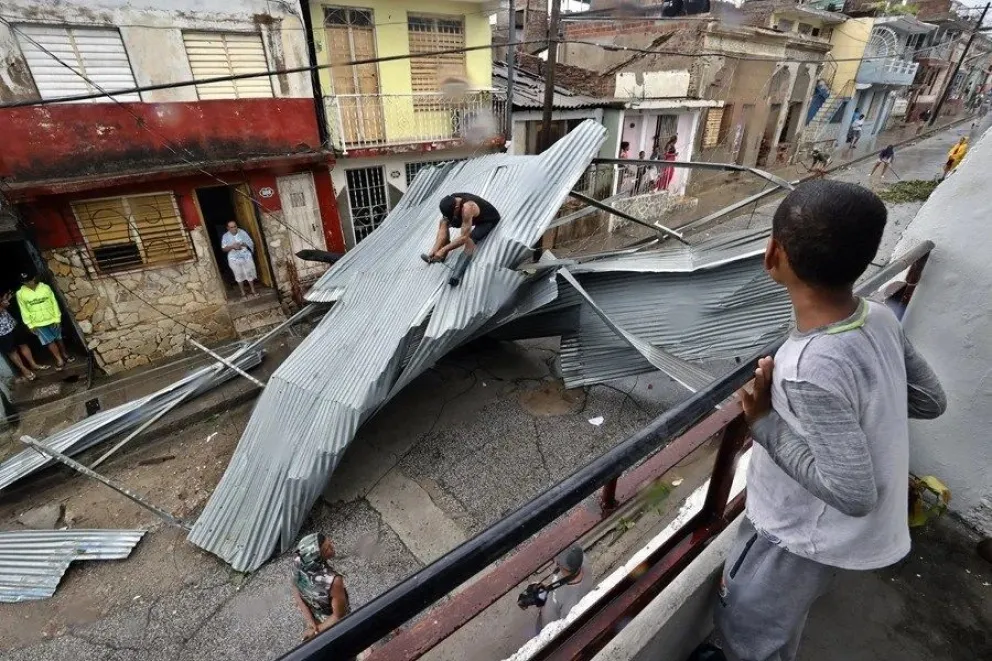 Personas recogen escombros en una calle afectada por el paso del huracán Melissa este miércoles, en Santiago de Cuba (Cuba). EFE 