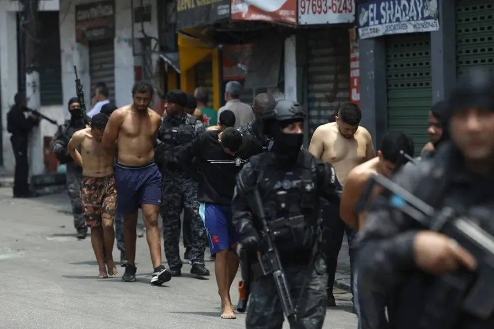 Policías escoltan a detenidos en el operativo. FOTO: EFE