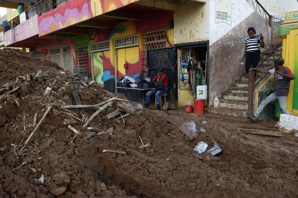 Varias personas caminan entre el lodo en una calle afectada por el huracán Melissa en Santa Cruz, Jamaica. EFE