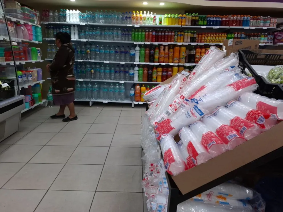 Una mujer observa envases reutilizables en medio de plásticos desechables. Foto: Sergio Mendoza