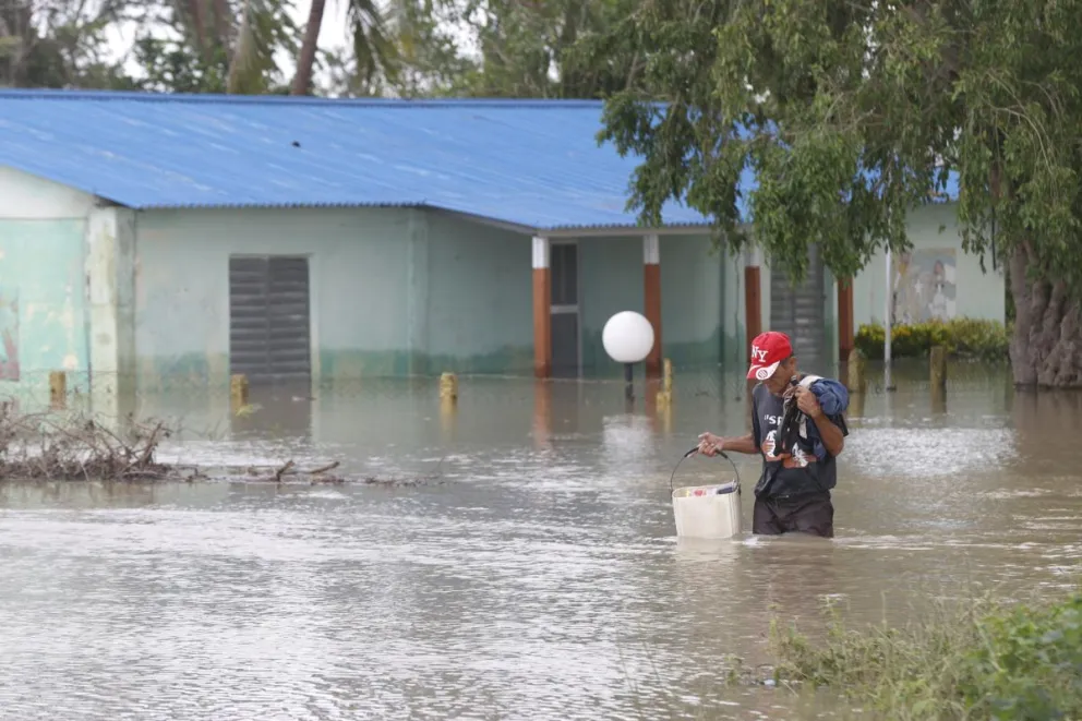 Una persona caminando frente a una casa inundada, en Cauto Cristo (Cuba). Foto: EFE