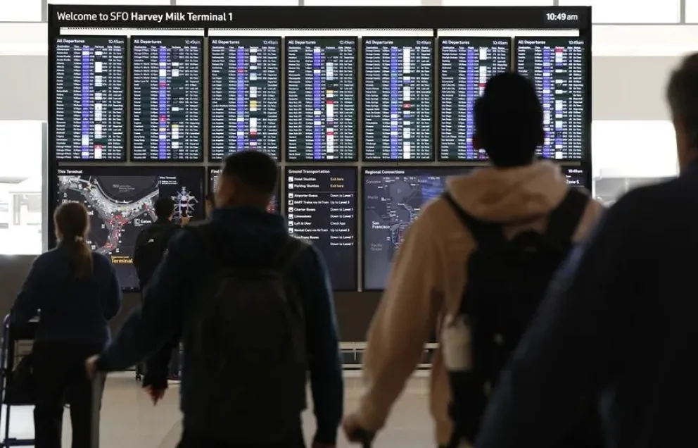 Personas observan una pantalla con el listado de vuelos, en el Aeropuerto Internacional de San Francisco. Foto: EFE