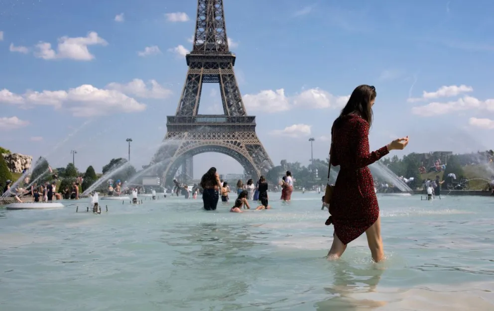 En la imagen de archivo, una mujer se refresca con el agua de la fuente de la Plaza del Trocadero, frente a la Torre Eiffel. Foto: EFE
