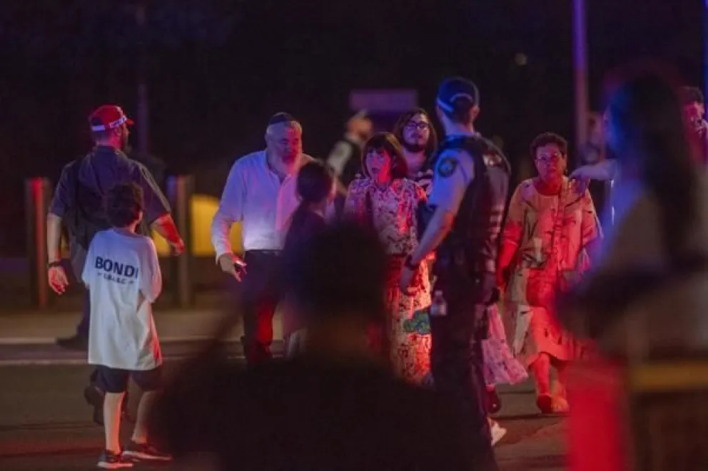 Un oficial de policía observa a la gente que desaloja la playa de Bondi en Sídney, Australia, donde este domingo al menos 10 personas han muerto. Foto: EFE