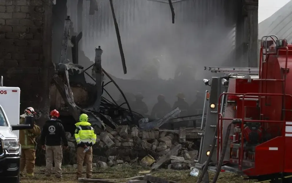 Bomberos trabajan en la bodega industrial donde cayó la aeronave. Foto: EFE