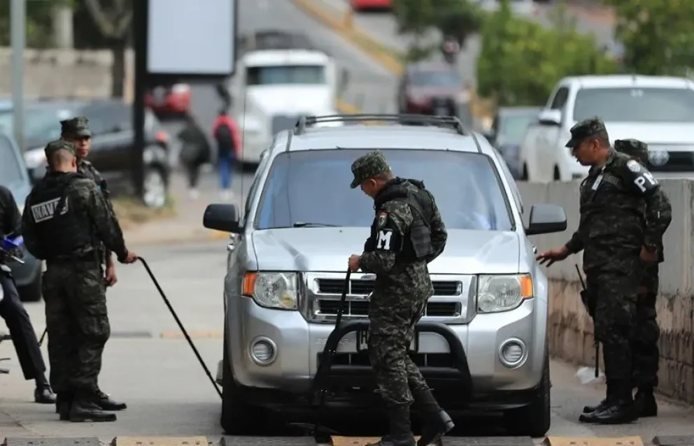 Integrantes de la Policía Militar de Honduras registran un vehículo en el ingreso del Instituto Nacional de Formación Profesional. Foto: EFE