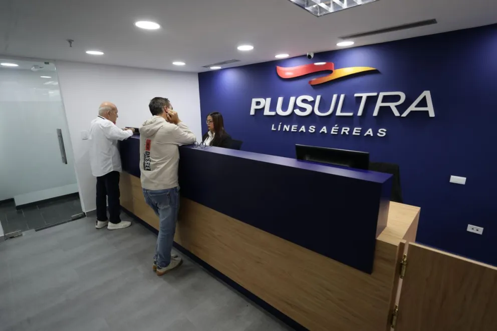 Personas verifican boletos en las oficinas de la aerolínea Plus Ultra en Caracas (Venezuela). Foto: EFE