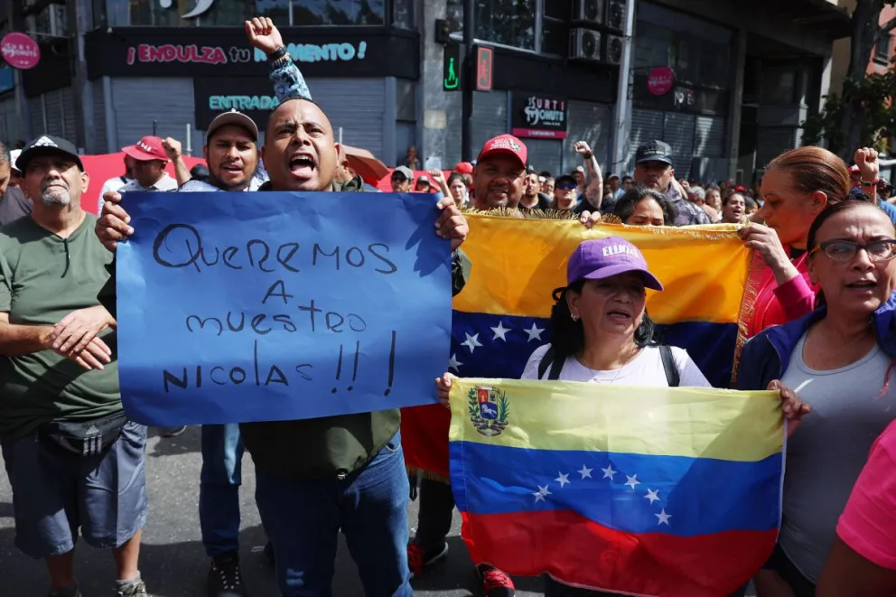 Simpatizantes del oficialismo sostienen carteles en inmediaciones del Palacio de Miraflores este sábado 3 de enero, en Caracas (Venezuela). Foto: EFE