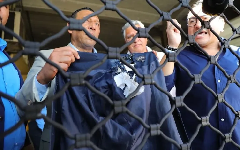 Personas muestran la chaqueta que usaba la diputada López, luego de ser afectada por un artefacto explosivo. Foto: EFE