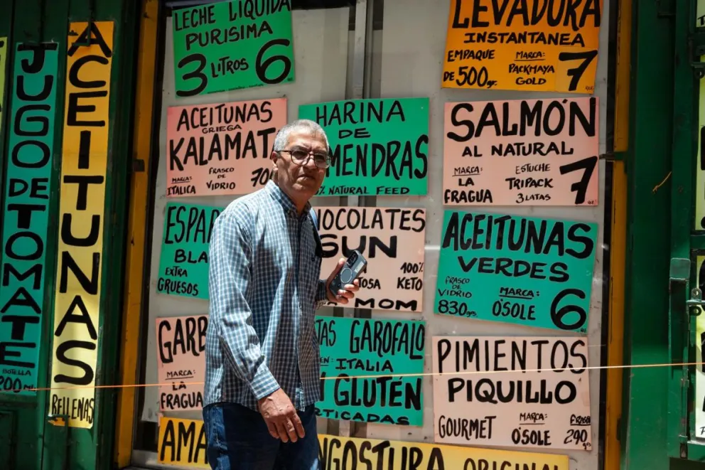 Una persona caminando frente a carteles con precios de alimentos, en Caracas (Venezuela). Foto: EFE 