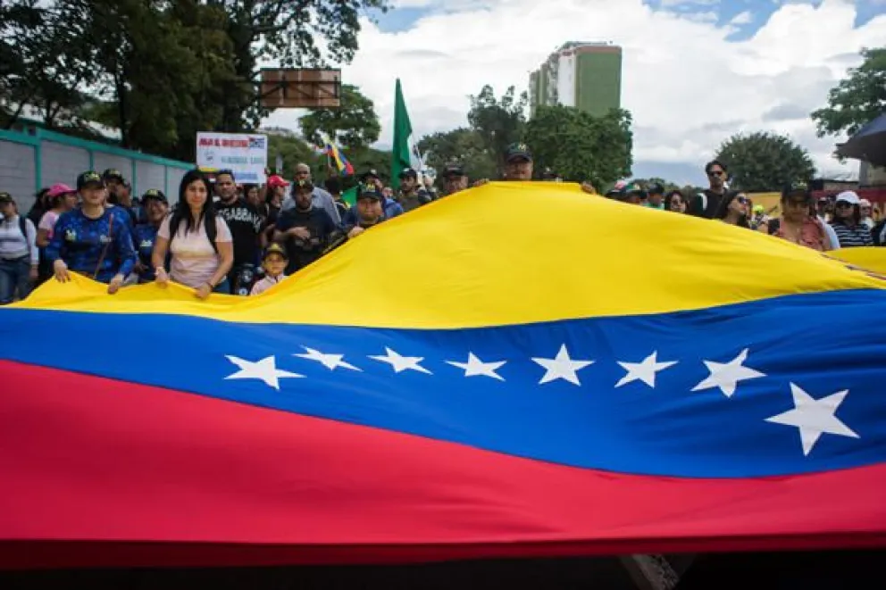 Personas sostienen una bandera durante una manifestación este sábado, en Caracas (Venezuela). EFE/ Boris Vergara