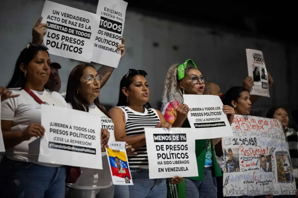 Familiares de los presos políticos sostienen carteles afuera de El Helicoide el lunes en Caracas. Foto: EFE