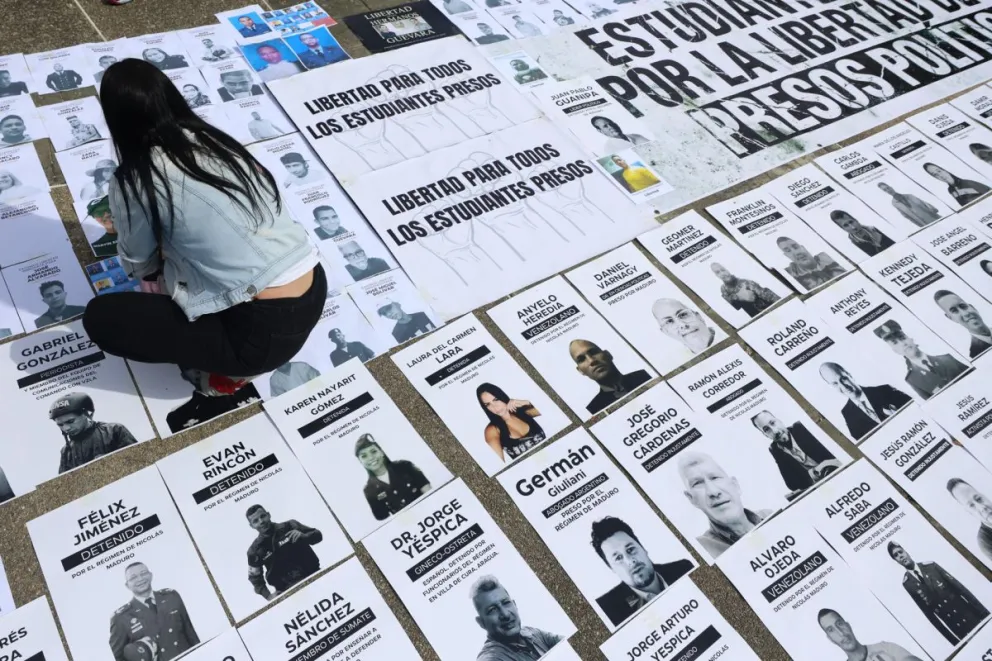 Una persona organiza carteles con imágenes de presos políticos este martes, en la Plaza del Rectorado UCV, en Caracas (Venezuela). Foto: EFE