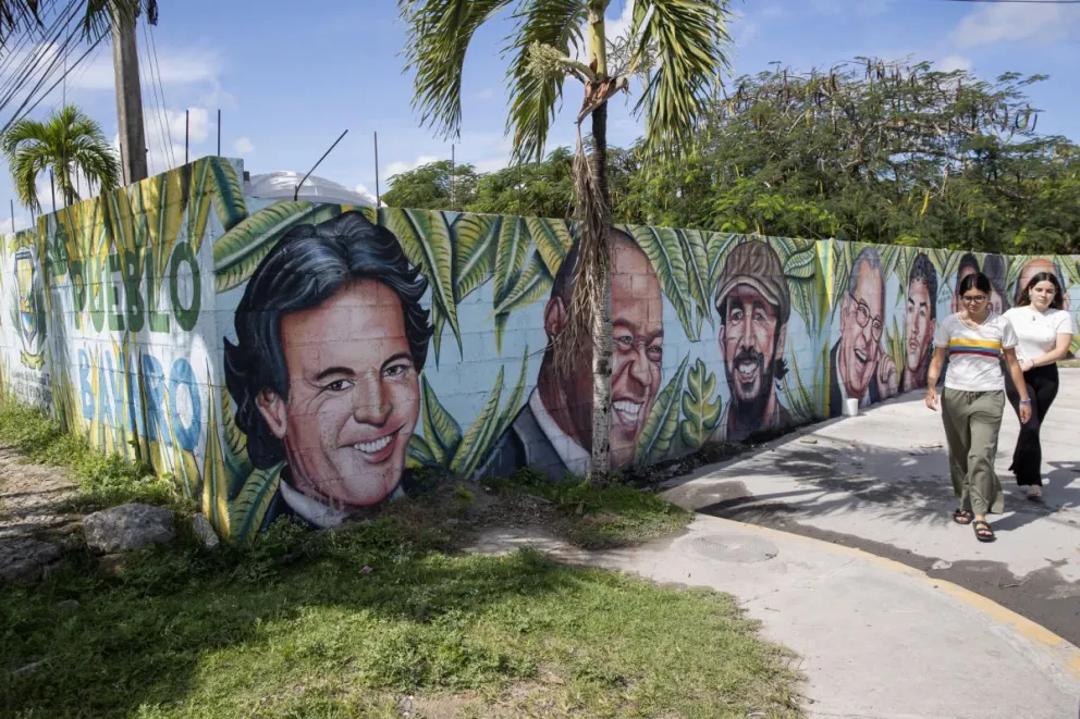 Personas caminan frente a un mural con los rostros de los artistas Julio Iglesias y otros en Punta Cana. Foto: EFE