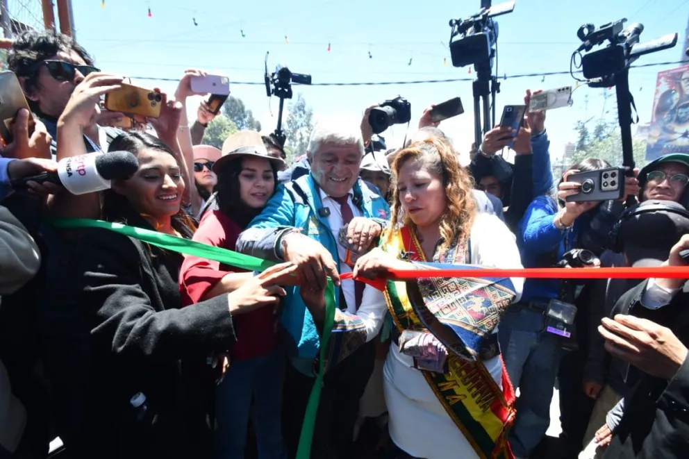 El alcalde Iván Arias corta la cinta para inaugurar la Alasita 2026, junto a la vocera Faval y una dirigente paceña. Foto: APG