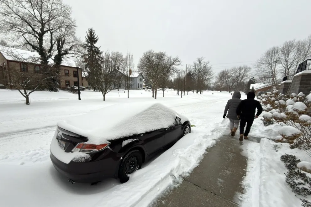 Dos personas caminan al lado de una calle afectada por la nieve este domingo en la ciudad de Hudson, Ohio. Foto: EFE