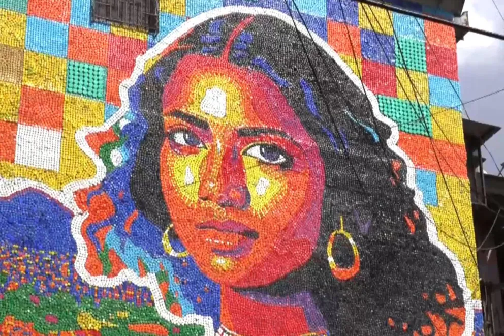 El artista venezolano Oscar Olivares elaboró un mural con más de 100.000 tapas plásticas de colores. Capturas de video: EFE