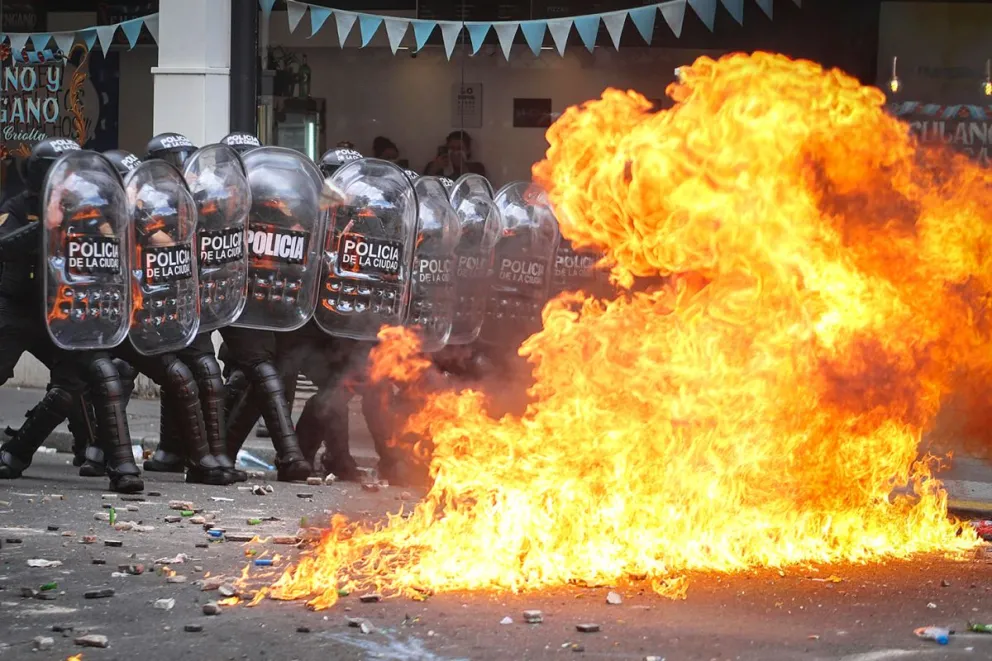 Integrantes de la Policía de Argentina se cubren durante un enfrentamiento con manifestantes este miércoles, en Buenos Aires (Argentina). Foto: EFE