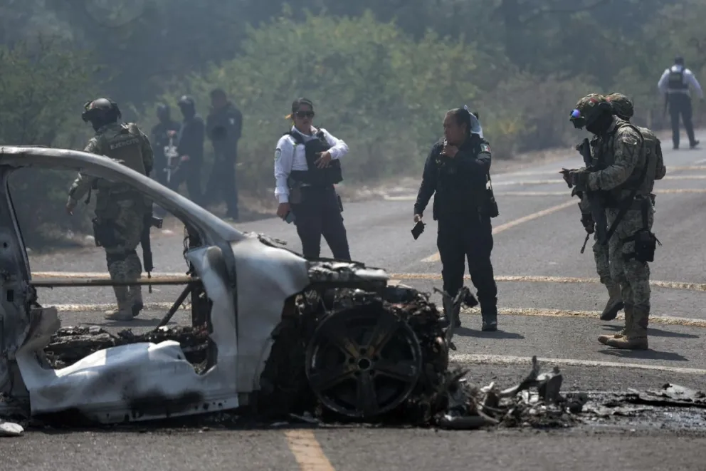 Integrantes de la policía de Morelia y del ejército trabajan en la zona donde fue incendiado un vehículo por presuntos integrantes del crimen organizado este domingo, tras el abatimiento de Nemesio Oseguera Cervantes, alias El Mencho, Foto: EFE