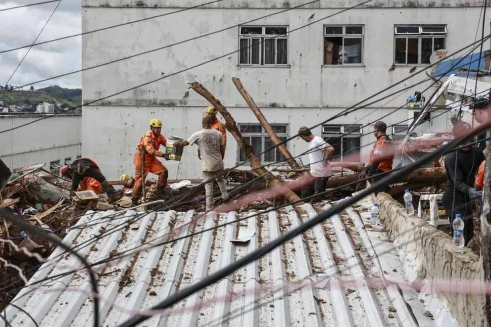 Integrantes del equipo de Bomberos y voluntarios remueven escombros durante las labores de rescate en una zona afectada por fuertes lluvias este miércoles, en Juiz de Fora (Brasil). Foto: EFE