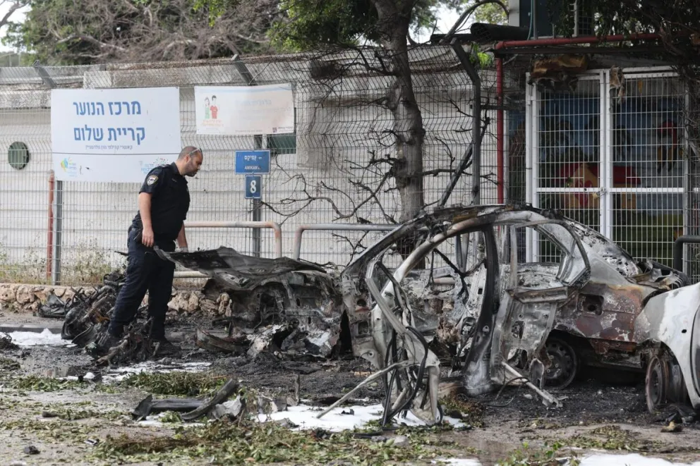 Un policía israelí inspecciona coches calcinados tras el impacto de fragmentos de un misil balístico iraní interceptado en Tel Aviv, Israel, el 15 de marzo de 2026. Foto: EFE