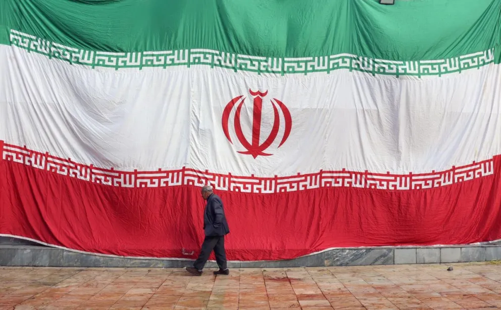 Un hombre pasa delante de una enorme bandera iraní, en una imagen de archivo. Foto: EFE