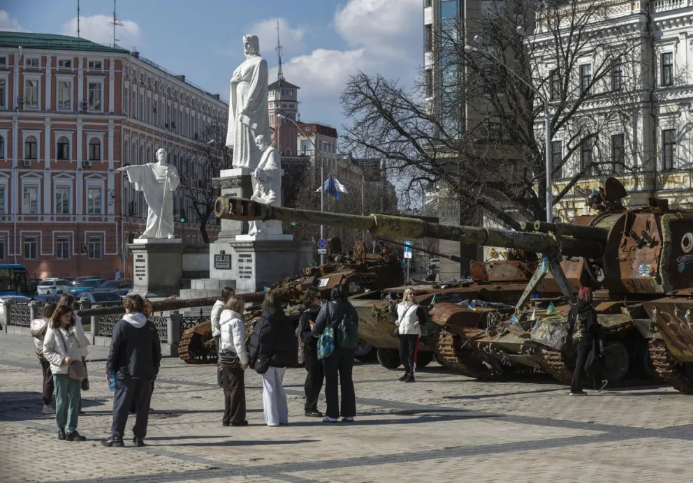 Varias personas pasan junto a vehículos de combate dañados exhibidos como parte de una exposición de equipo militar ruso destruido, en Kiev. Foto: EFE 
