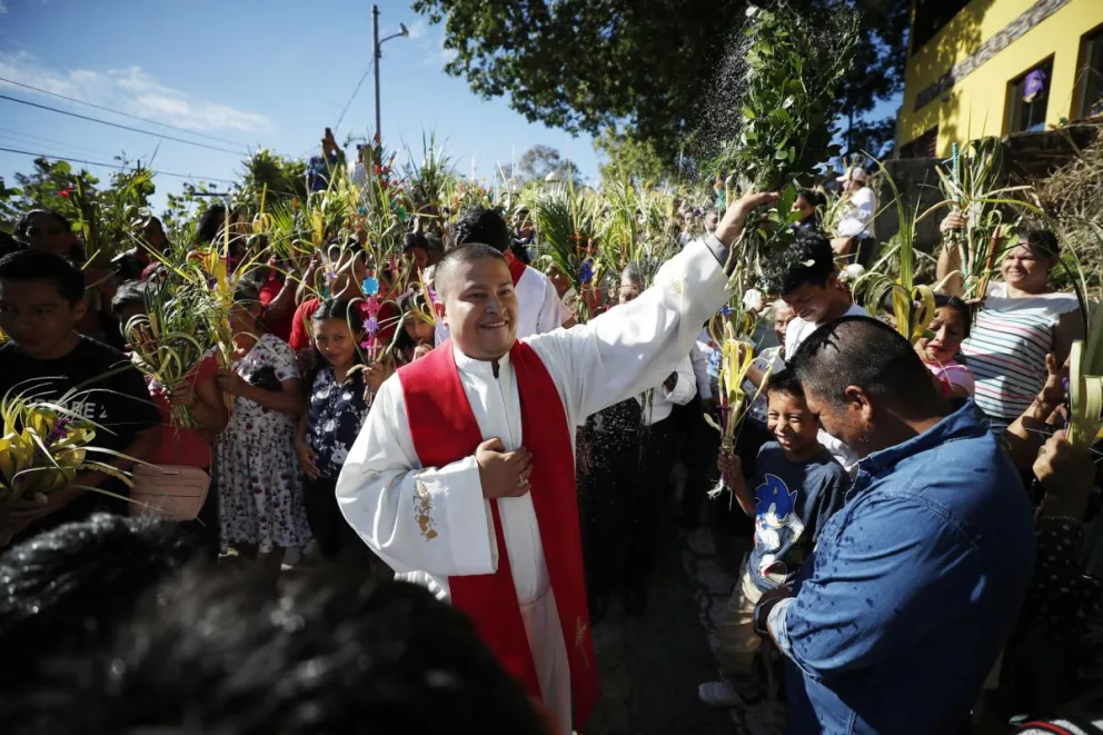 Un sacerdote esparce agua bendita durante la procesión del Domingo de Ramos en Nahuizalco (El Salvador). Foto: EFE