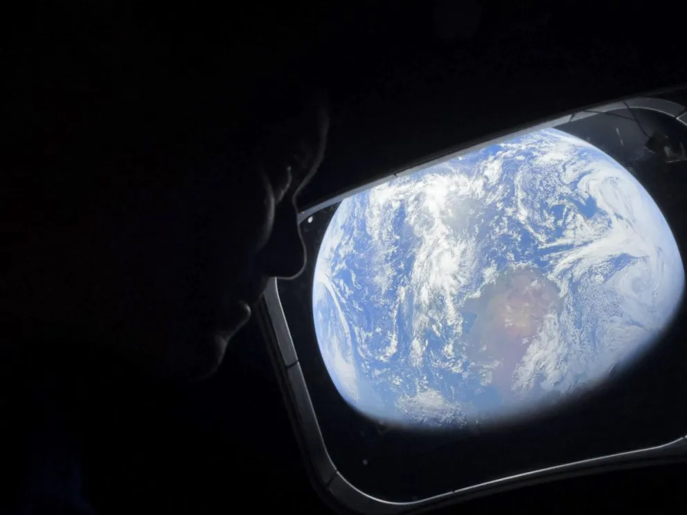 El comandante Reid Wiseman observa la Tierra mientras continúan adentrándose en el espacio hacia la Luna. Foto: EFE