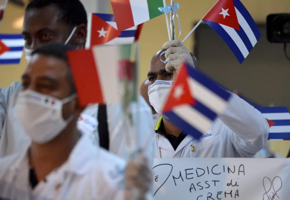 Imagen del 8 de junio de 2020 de médicos cubanos de una misión médica ondeando banderas cubanas tras su llegada de Europa a La Habana. Foto: EFE