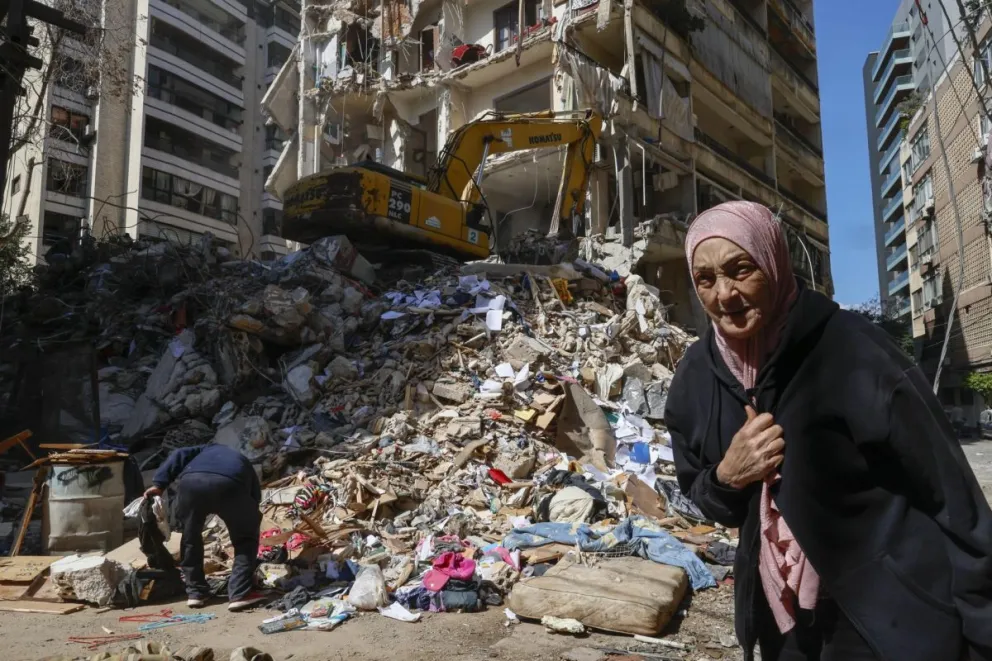 Una mujer camina este jueves junto a un edificio residencial destruido por un ataque aéreo israelí en el barrio Ain Mreisseh de Beirut. Foto: EFE