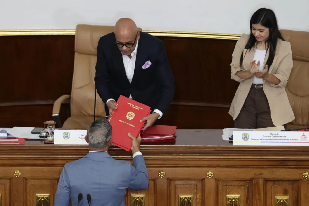 El diputado Giuseppe Alessandrello (abajo) entrega a Jorge Rodríguez el informe para la designación del defensor del pueblo y fiscal general en Caracas. Foto: EFE.