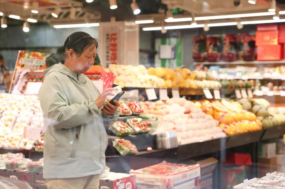 Una mujer compra en una frutería en Pekín, China. Foto: EFE 